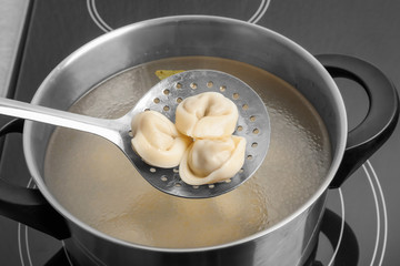 Cooked dumplings on skimmer over saucepan