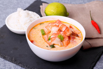 A bowl of fish soup with salmon, shrimps and potato at natural white background