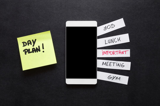 White paper sheets with written different workday actions on the office desk. Plans about job, lunch, meeting and other important things. Empty place for text on black screen. Schedule concept.