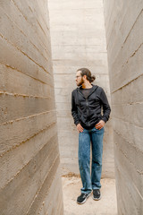 White young handsome man standing near the wall and look up. Portrait of fashion guy in blue jeans and casual wear smiling