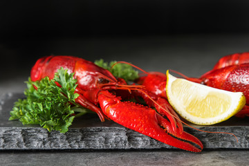 Delicious boiled crayfish close-up with lemon and parsley. Dark background. Dinner with seafood.