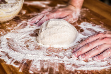 male hands kneading dough on wooden table. mass of dough on a table