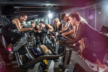Fototapeta na wymiar Group of fit people cycling in fitness club.