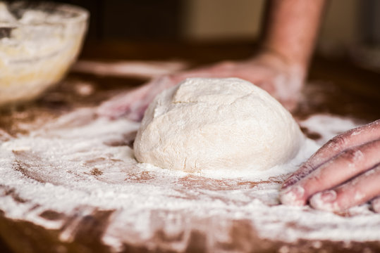 male hands kneading dough on wooden table. mass of dough on a table