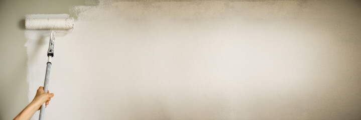 Hand painting wall with paint roller, pastel color. Appartment renovation, repair, building and...