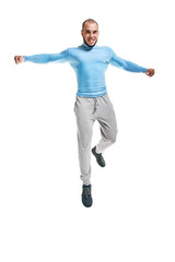 Cheerful man jumping. Healthy fit man warming-up and jumping on white background