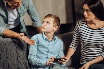 Stop it. Strict young father scolding his son for binge-playing games on the phone while the boy looking at him indignantly