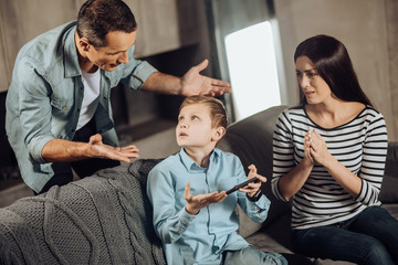 Put down phone. Strict young father reprimanding his son for playing games on the phone too much, the boy being offended, while the mother feeling sorry for the son