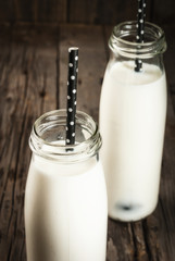 Two bottles of organic rustic milk on an old wooden table. Copy space close view
