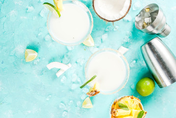 Tropical drink, Frozen Coconut Pineapple Margaritas with frozen pina colada, tequila, pineapple juice and lime,  light blue background, copy space top view - obrazy, fototapety, plakaty