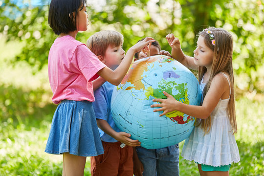 Kinder halten zusammen eine Weltkugel