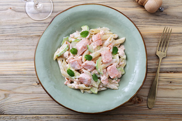 pasta italiana penne con salmone e panna su sfondo tavolo di cucina
