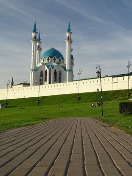 Widok Wielkiego Meczetu w Kazaniu, stolicy Tatarstanu w  Federacji Rosyjskiej, na pierwszym planie brukowany chodnik wiedzie do zielonego wzg&oacute;rza na kt&oacute;rym jest meczet, błękitne niebo 