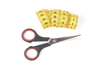 Sewing small scissors with yellow measuring tape on a white background, sewing equipment