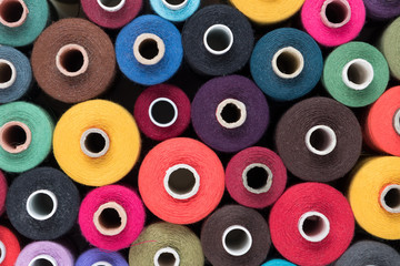 Stacked colored sewing threads, textile background and colourful wallpaper