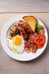 Full English or Irish breakfast: sausages, bacon, egg, mushrooms, tomatoes and toasts. Nutritious morning meal