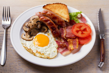 Full English or Irish breakfast: sausages, bacon, egg, mushrooms, tomatoes and toasts. Nutritious morning meal