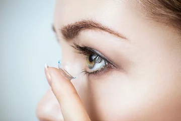 Close-up shot of young woman wearing contact lens. © Dmitrii Kotin