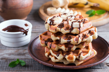 Wafers with banana and chocolate sauce on a gray wooden background