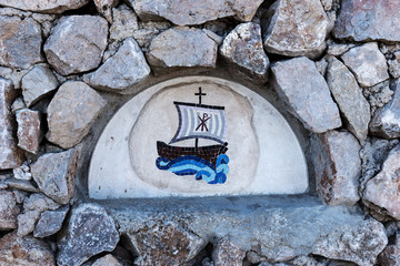 Closeup blue sailing ship mosaic tiles on an old stone wall