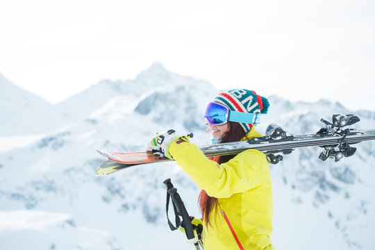 Photo of smiling woman in mask with skis on her shoulder