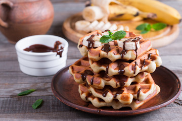 Homemade Belgian waffles with chocolate sauce and banana slice on a plate