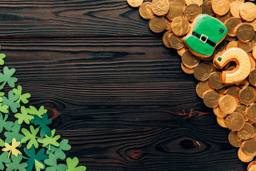 top view of shamrock and golden coins on wooden table, st patricks day concept