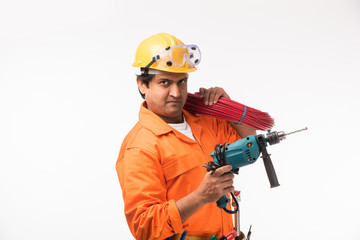 Indian electrician engineer in action with wire cutter, drilling machine etc, standing isolated over white background

