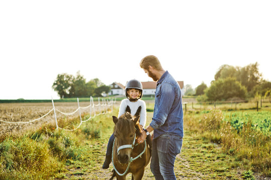 Man helping his daughter ride horse in Friseboda, Sweden