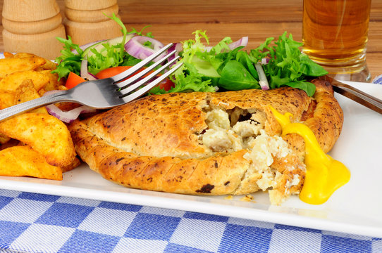 Pasty and potato wedges meal with fresh salad isolated on a white background