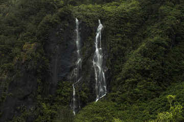 Doble cascada cayendo por la ladera de una montaña llena de vegetación