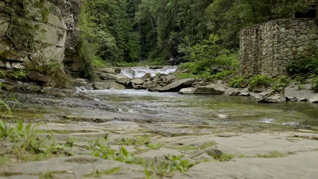 Sliding video of mountain river in canyon with man made stone fence in side