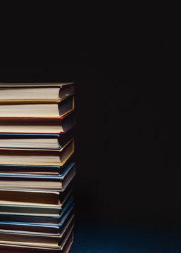 Concept Of Education And Knowledge. Tower Of Old Multicolored Books On A Black Background