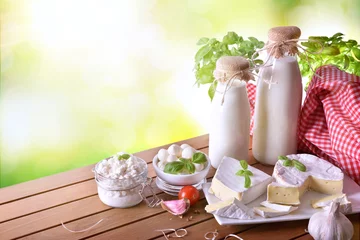 Abwaschbare Fototapete Milchprodukte Handwerklicher Käse auf Holztisch in der Natur