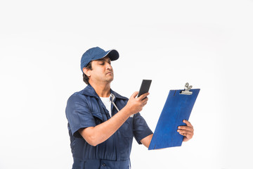 Indian happy auto mechanic in blue suit and cap holding spanner tool in action, isolated over white background