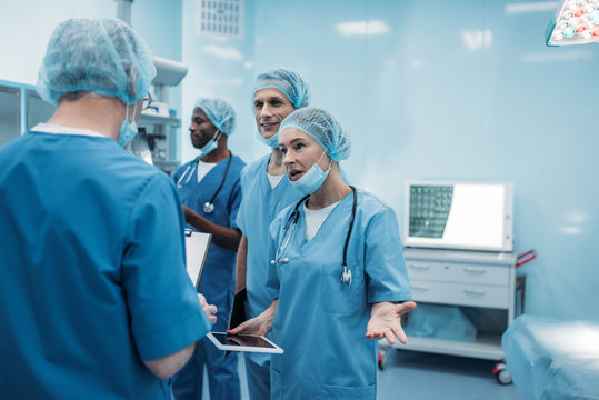 Four Multiethnic Surgeons Talking In Operating Room