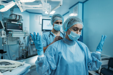 Fototapeta na wymiar doctor helping to wear surgical uniform for surgeon