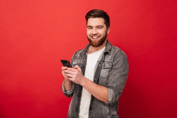 Smiling bearded man holding smartphone and looking at the camera