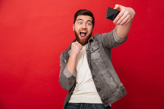Happy screaming man making selfie on smartphone with open mouth