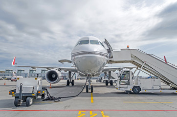 Passenger airplane in the parking at the airport with a nose forward and a gangway.