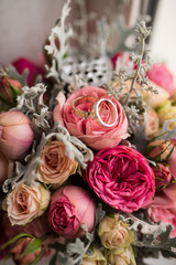 Golden wedding rings lie in a bud of pink rose. Wedding rings lie on a flower bud