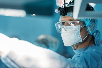 handsome surgeon in medical mask and glasses looking away