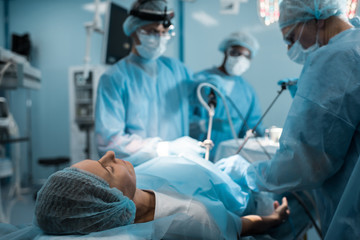 multiethnic surgeons operating patient in operating room
