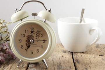 A white coffee cup with Alarm clock on the wood on white background, Vintage filter style, Vintage concept