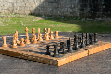Antique wooden chess board on a wooden table outdoor, strategic activity in the open air