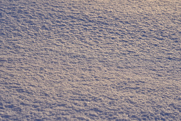 Natural background - ice surface of snow illuminated by the rays of the evening sun. The sun's rays bouncing off the gleaming crystals loose ice..