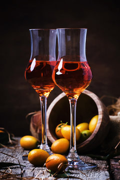 Traditional greek kumquat liqueur in shot glass, vintagen background, rustic style, selective focus
