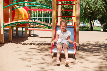 Fototapeta na wymiar Little girl is sliding at playground