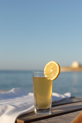 Sunbed with polo shirt and glass of cold drink on it at sea beach