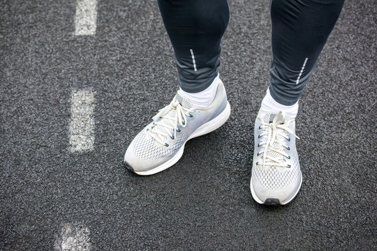 Close up of legs in running shoes standing on asphalt.